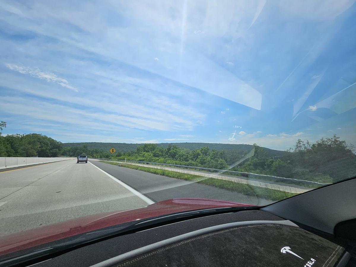 Tesla Model 3 cruising northbound on a sunny June highway through Pennsylvania hills
