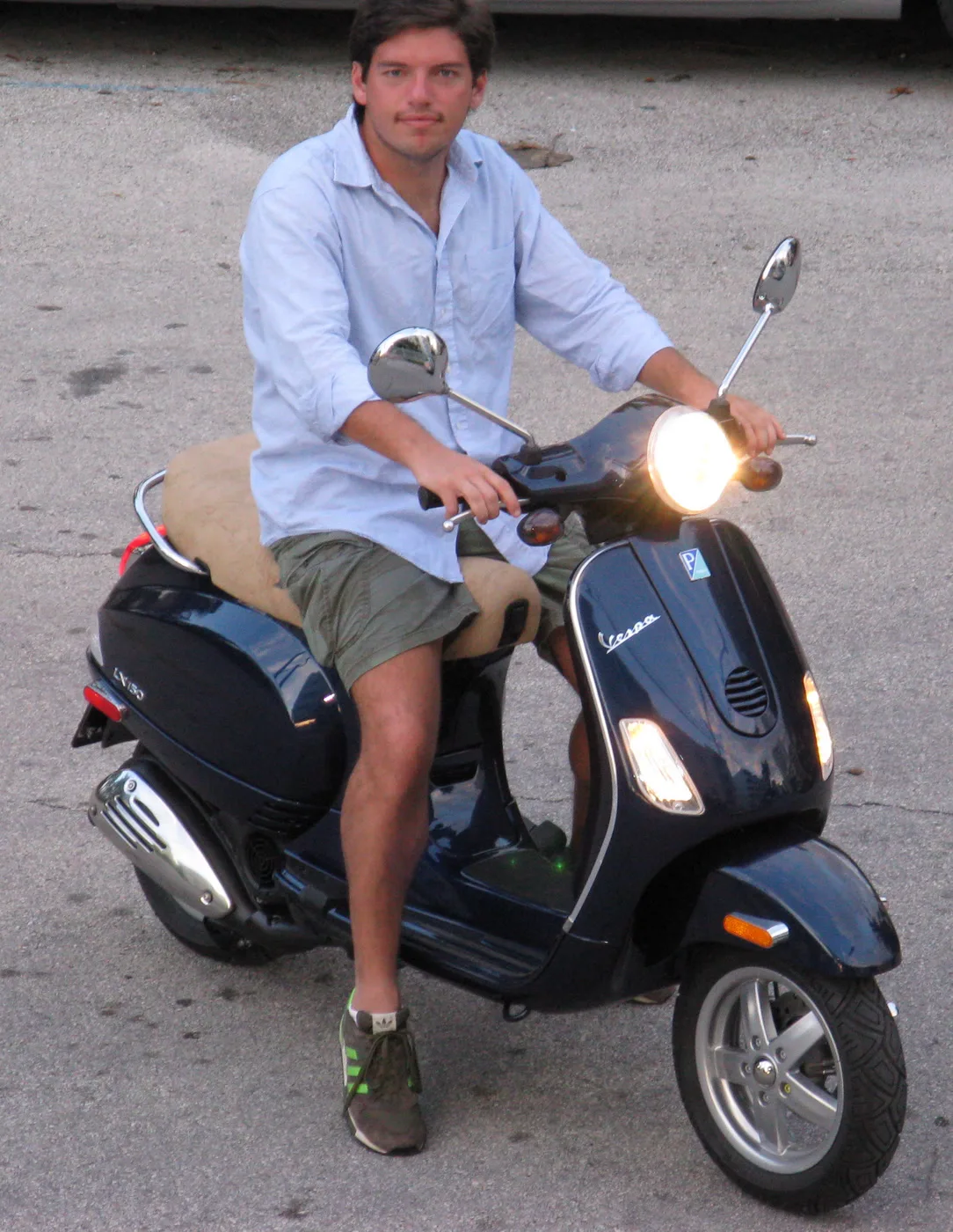 Rider on a dark Vespa LX 150 with legs in front and a foot on the floorboard, not on pedals